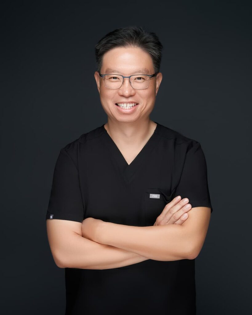 Smiling male doctor in black scrubs with arms crossed