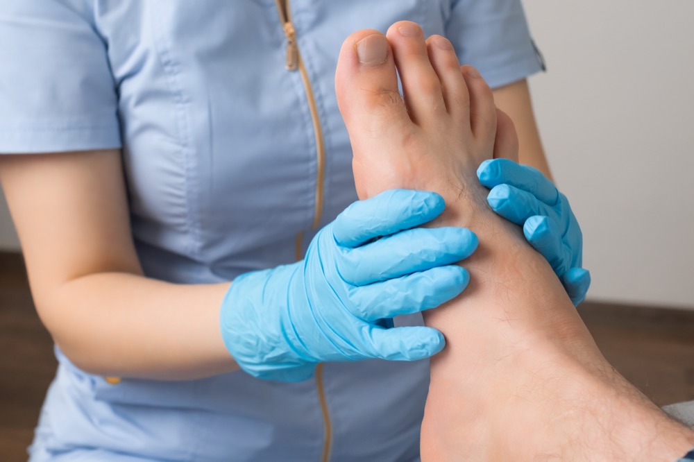 Medical professional examining patient's foot with gloved hands