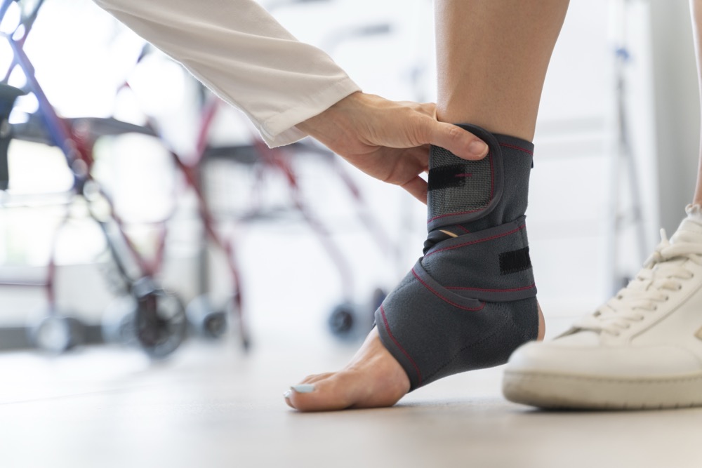 Doctor fitting ankle brace on patient in medical facility