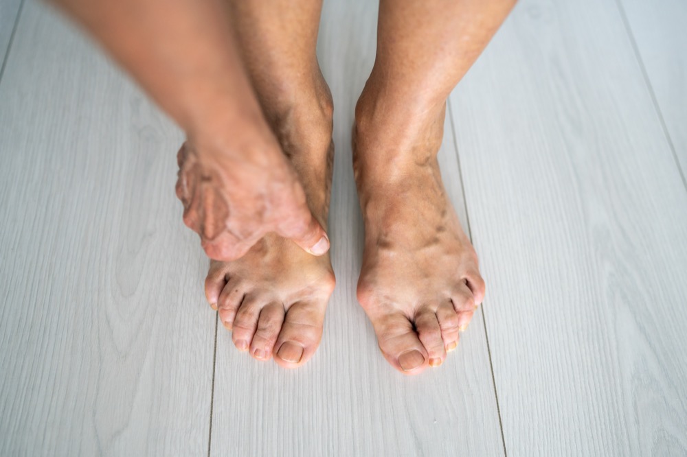 Bare feet with visible veins on wooden floor