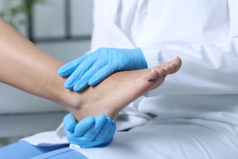 Doctor in blue gloves examining patient's foot and ankle