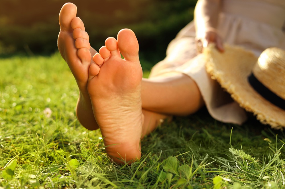 Bare feet of woman relaxing on green grass outdoors