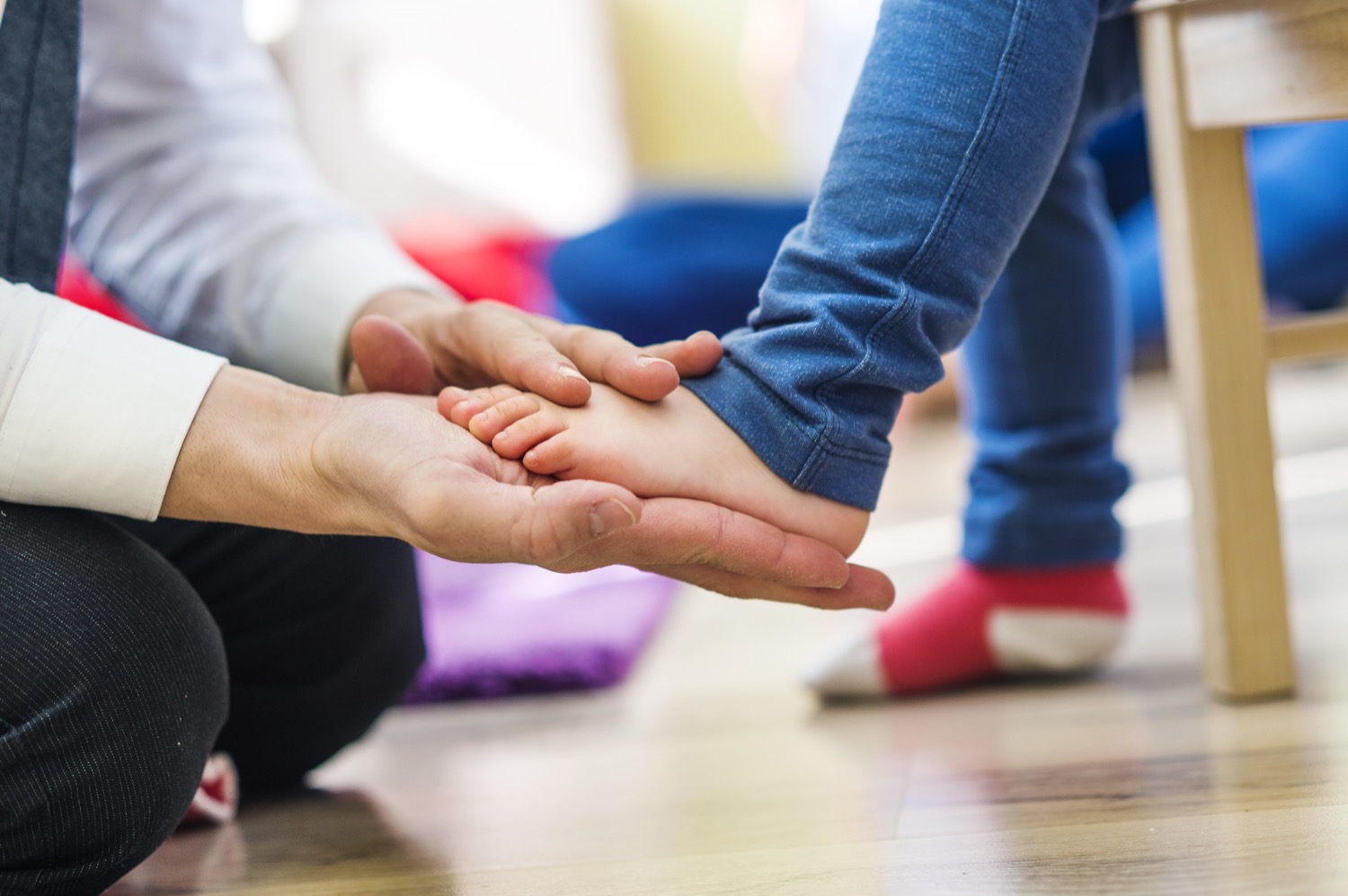 Adult gently holding a small child's hand indoors