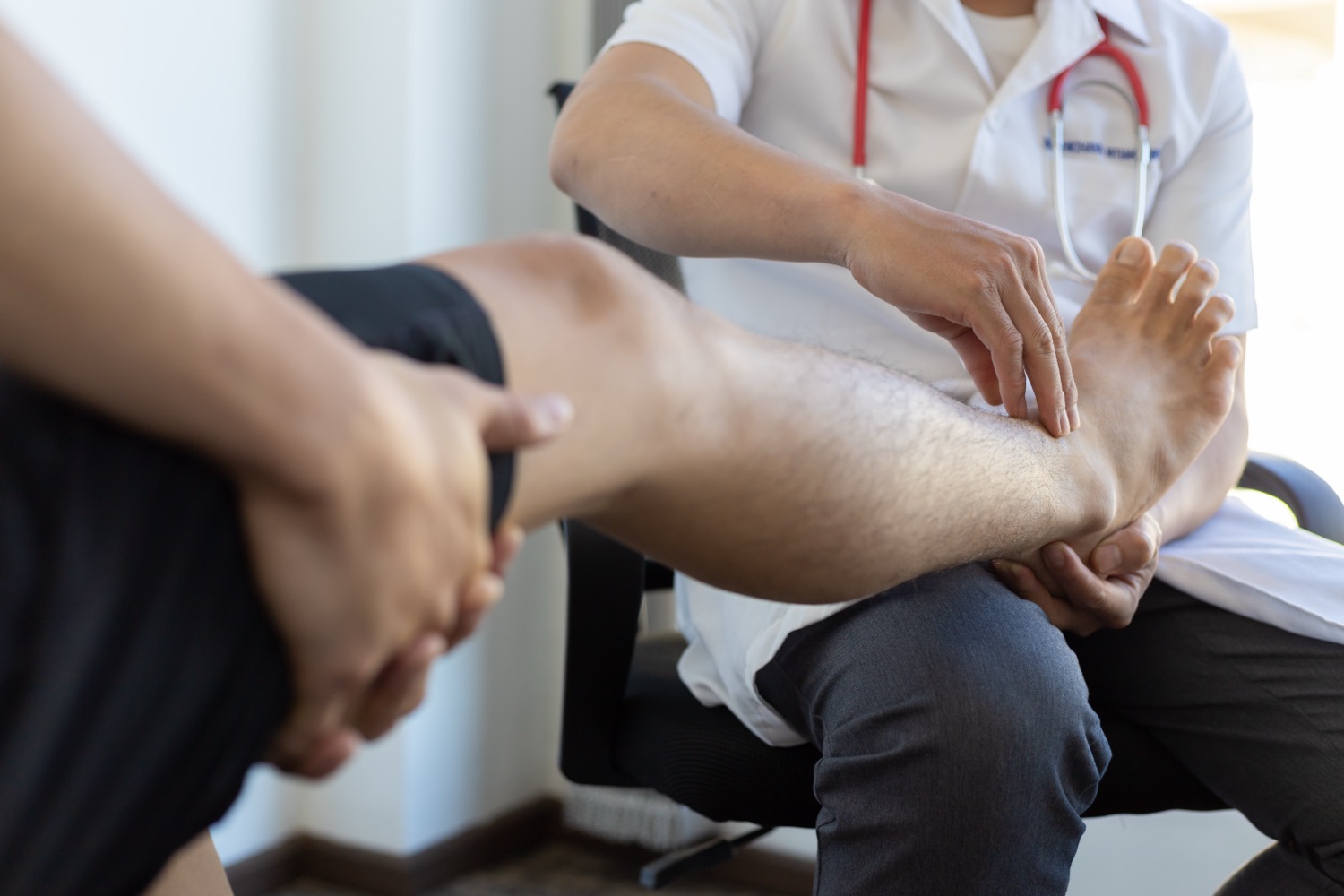 Doctor examining patient's foot and ankle in clinic