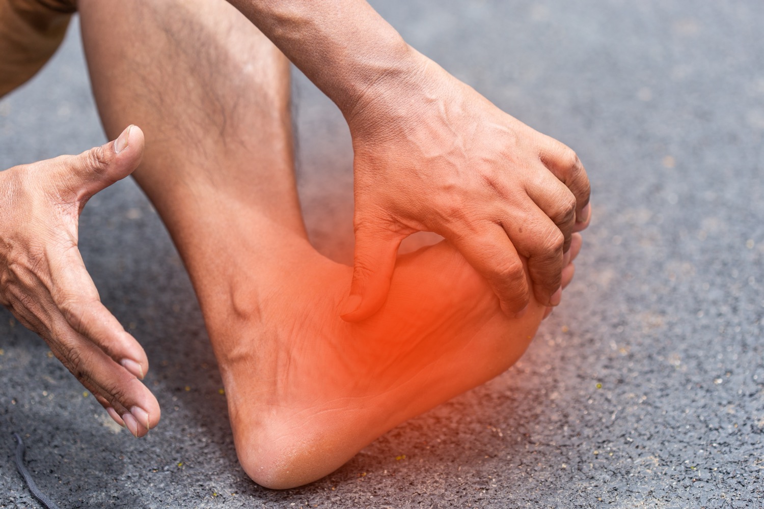 Person clutching painful red inflamed ankle and heel area