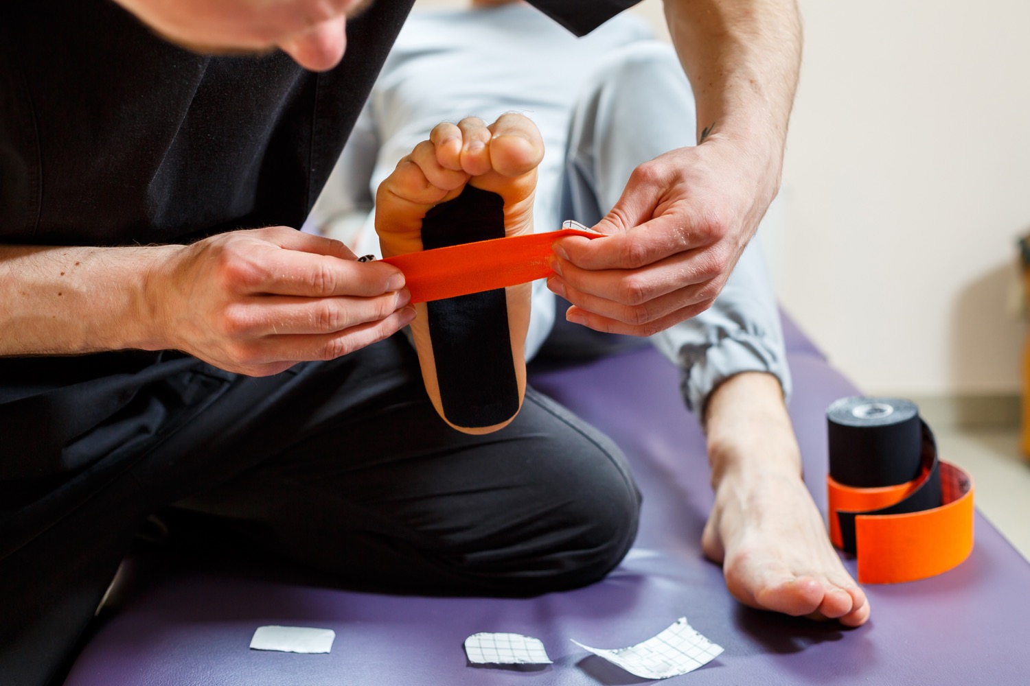 Therapist applying kinesiology tape to patient's foot