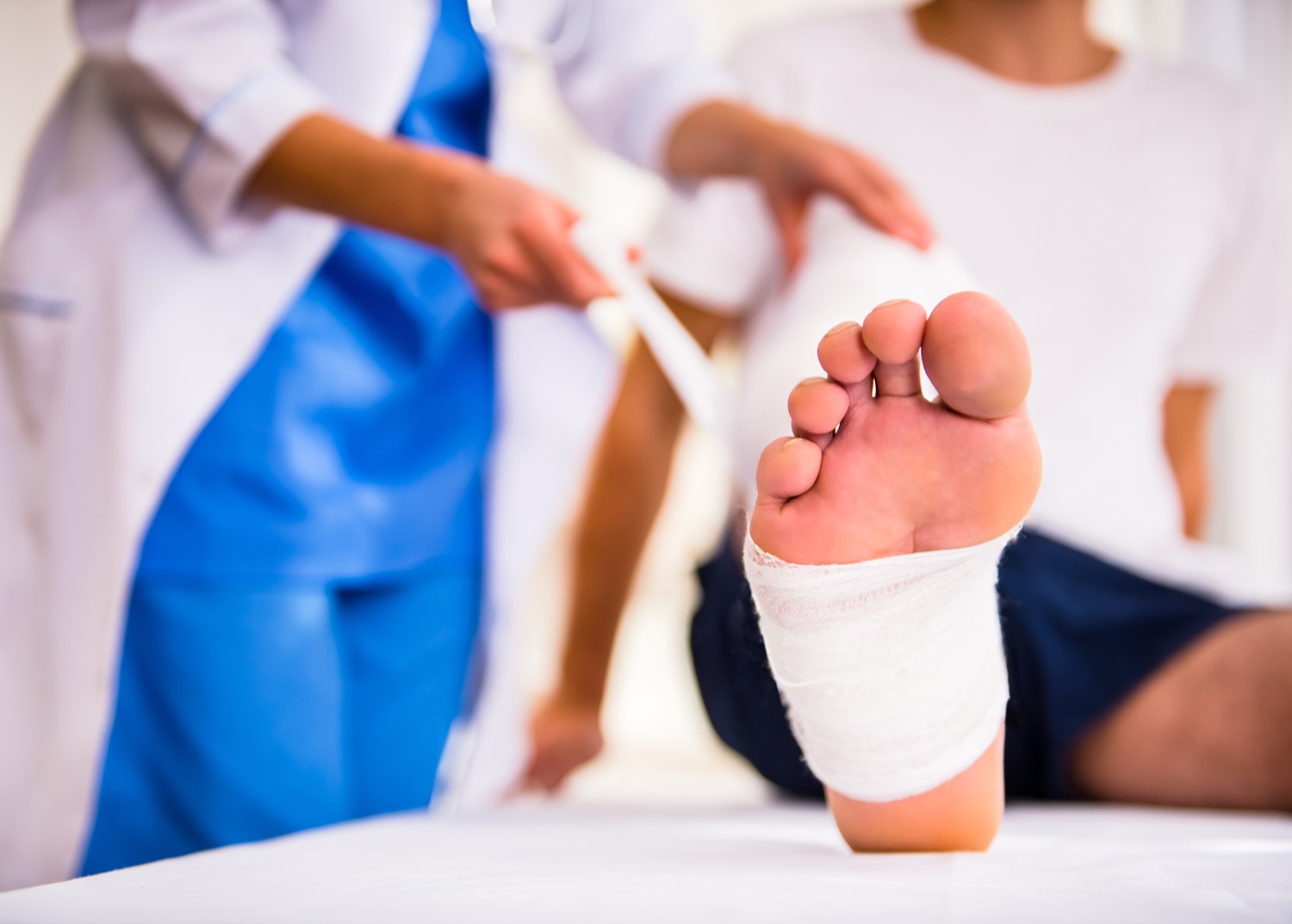 Doctor wrapping bandage around patient's injured foot
