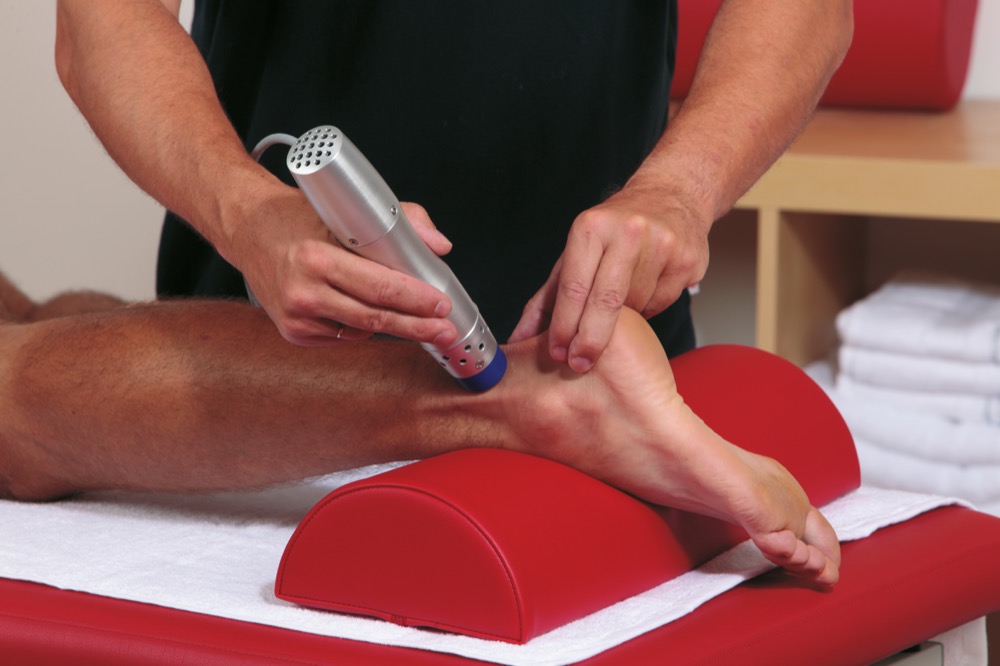 Therapist applying shockwave therapy device to patient's foot