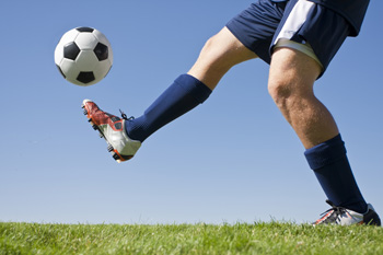 Soccer player kicking black and white ball on grass