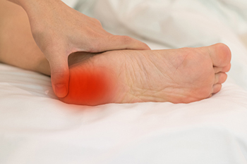 Person holding foot with highlighted pain area on sole