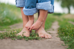 Adult and child bare feet standing together on dirt path