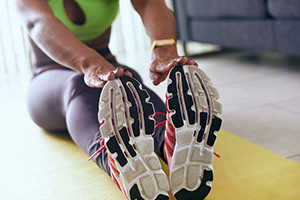 Woman stretching forward on yoga mat in athletic wear