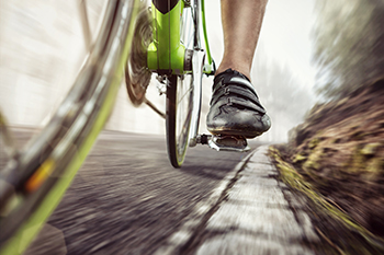 Close-up of cyclist's foot pedaling a green bicycle
