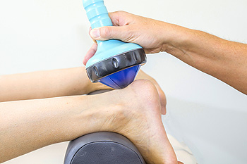 Therapist applying ultrasound therapy device to patient's ankle