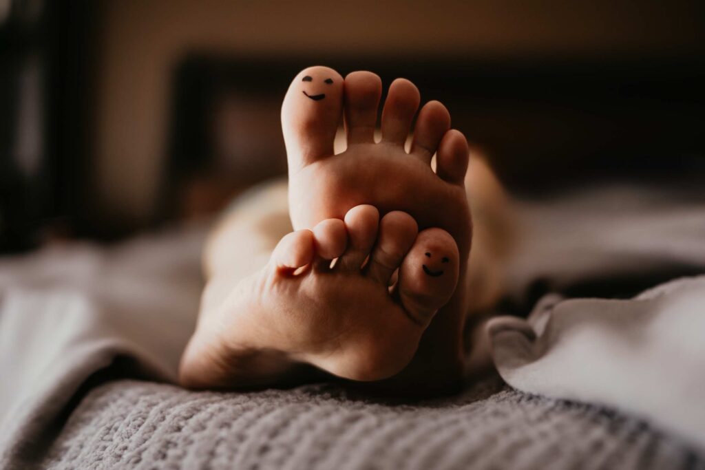 Bare feet with smiley faces drawn on toes