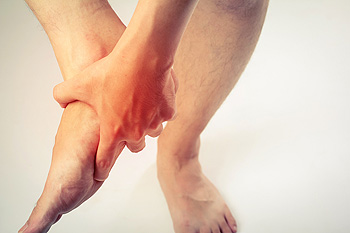 Person holding ankle in pain with red inflammation highlighted