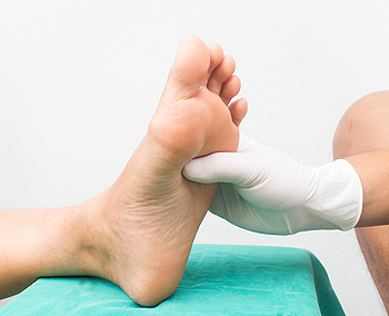 Medical professional examining patient's foot sole with gloves