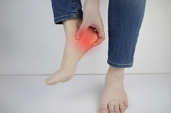 Person holding painful red heel indicating foot pain
