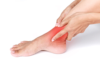 Person holding painful inflamed ankle with red highlighted area