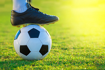 Soccer player's foot resting on black and white ball