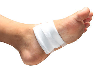 Foot with white medical bandage wrap on white background