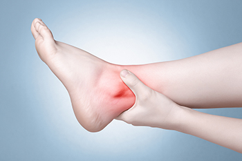 Person holding painful inflamed ankle with red highlight