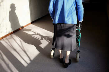 Elderly person walking with a rollator walker indoors