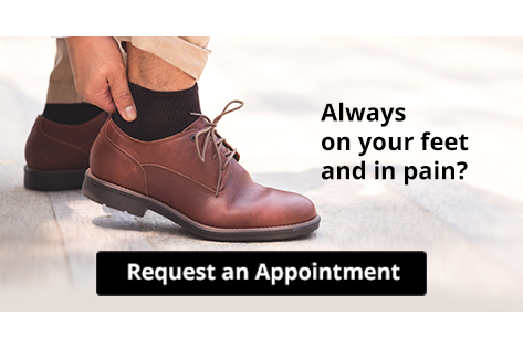 Person rubbing sore ankle while wearing brown dress shoe